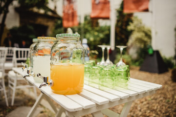 table in the garden with drinks, lemonade, water, cut oranges and glasses