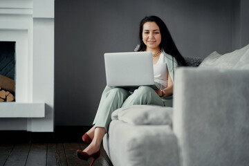 online training for working on a laptop computer on a new project in a stylish office. A young woman of Caucasian appearance is sitting on the sofa. a favorite work, a comfortable business suit