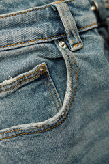 Abstract background with blue jeanse, close-up. Fashion details. Vertical photo