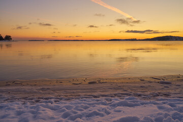 The coast of the sea in ice and in the snow at sunset.
