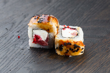 Close-up of uramaki sushi rolls with red caviar, salmon, tuna, cucumber and avocado isolated on black background. Delicious traditional japanese food with sushi rolls.