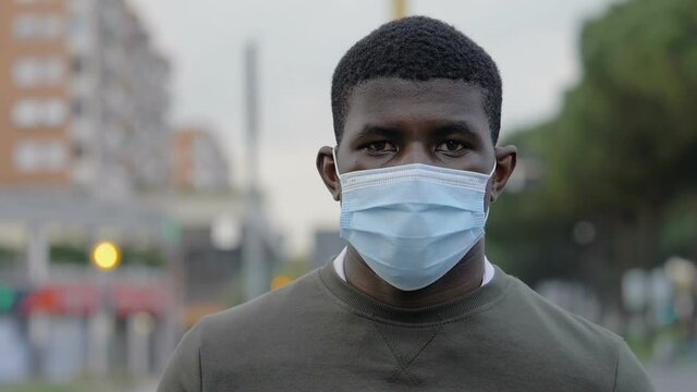 pandemic, 2021 - serious blackman with mask stares at camera on the street