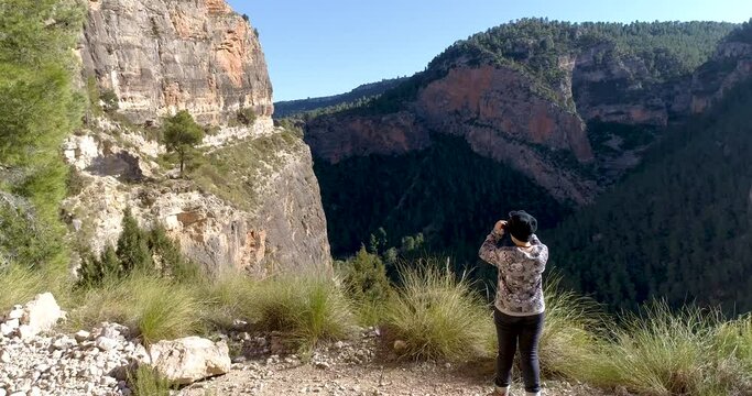 dron volando sobre adolescente mirando barranco de piedra con prism&aacute;ticos
