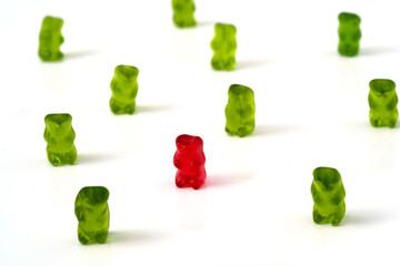 Ein rotes Gummibärchen mit dem Corona virus infiziert und einige grüne Gummibärchen die die abstandsregel einhalten