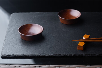 chopsticks on a black stone board. sushi sticks on a stand with a plate for sauce