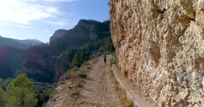 dron vuela por detr&aacute;s a adolescente senderista en barranco