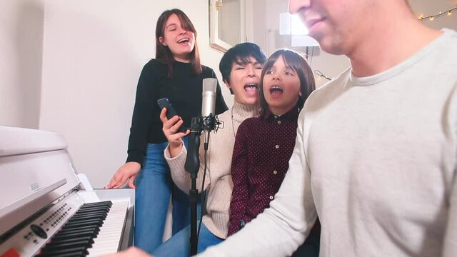 Cheerful group singing to the accompaniment of the piano. The company has fun with favorite songs. The child tries to sing loudly, recording is made using a microphone.