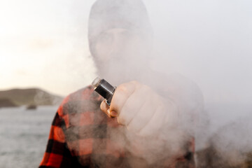 Clenched fist holding an electronic cigarette wrapped in steam. person quitting smoking. boy vaping.