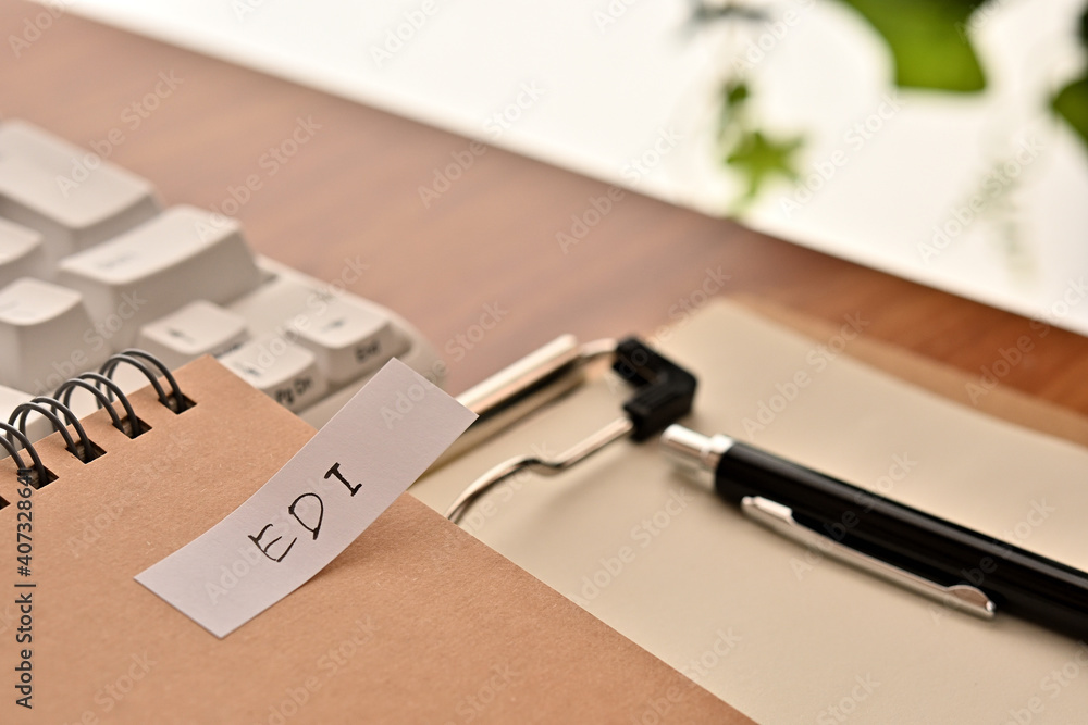 Poster a sticky note labeled edi is taped to the edge of a notebook on the desk.that's an acronym for elect