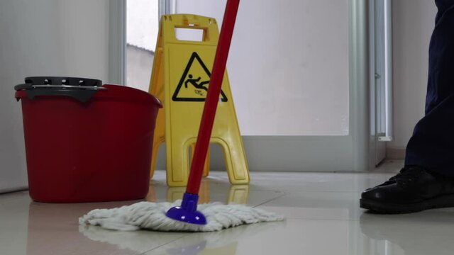 Cleaning Floor With Caution Wet Floor Sign In Office with mob