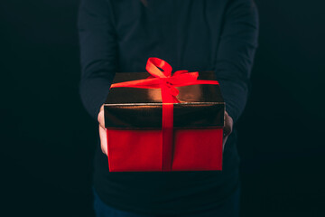 Close up photo of female hands holding red gift box.