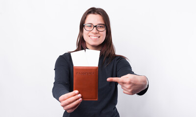 Happy girl pointing at passport and tickets over white background.