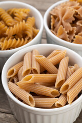 Narrow focus closeup of assorted whole wheat pasta on bowls