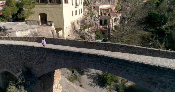 plano cenital de dron de mujer con mascarilla covid-19 sobre puente antiguo