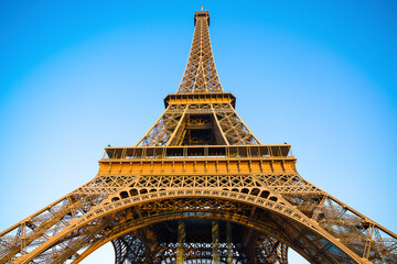 Fototapeta na wymiar Detail bottom view of Eiffel Tower on the blue sky background in sunset light