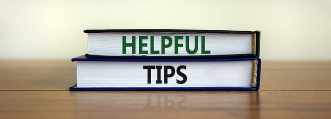 Helpful tips symbol. Books with words 'Helpful tips'. Beautiful wooden table, white background. Business and helpful tips concept. Copy space.