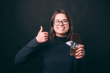 Happy young woman showing thumb up and holding chocolate.
