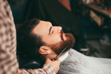 Selective focus of barber making beard haircut with scissors.