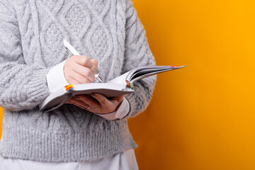 Close up photo of woman making notes in agenda or planner.