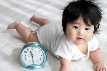 赤ちゃんと時計、育児イメージ（0歳、生後6カ月、女の子、日本人）
