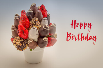 Happy birthday greeting card with red brush lettering; A bundle of edible flowers, arrangement of strawberries covered with chocolate isolated on white background