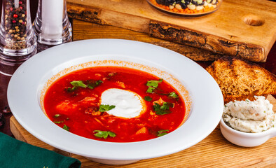 Traditional Ukrainian Russian borscht or beetroot red soup with sour cream in white plate