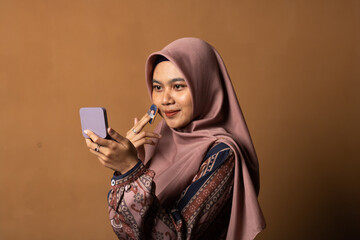 Portrait of beautiful asian woman applying powder puff at cheek makeup of cosmetic on gold background