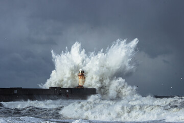 powerful wave crashing on lighthouse in heavy winter storm