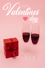 red wine in glasses near gift and happy valentines day lettering on pink