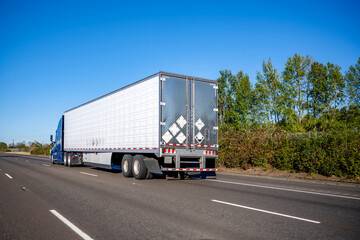 Bonnet big rig blue semi truck tractor transporting commercial cargo in refrigerator semi trailer...