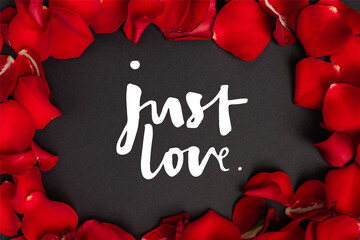 Top view of just love lettering in frame with rose petals on black