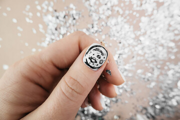neat fresh white manicure with pattern of stars and comets by stamping on thumb on beige background...