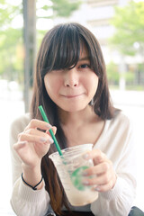 カフェでドリンクを飲む笑顔の女性　ロングヘア
