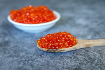 Red caviar in a wooden spoon on a blue background. Close-up.