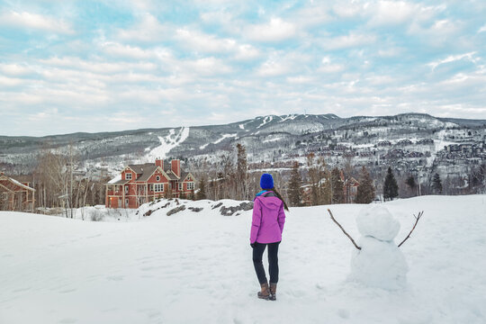 Mont-Tremblant landscape mountain view in winter. Woman tourist walking in snow at famous Canada ski resort in Quebec, North America.