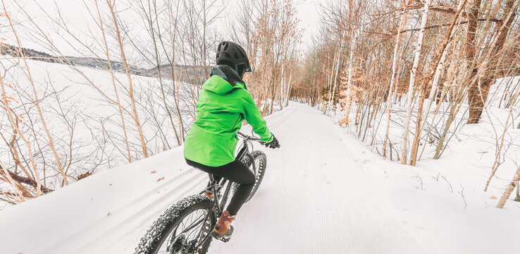 Fat bike winter sport biker cyclist biking girl riding on snow trail. Outdoor sport in nature forest background panoramic landscape.