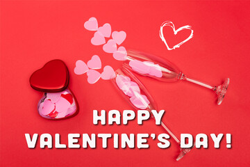 Top view of pink hearts in champagne glasses near metallic box and happy valentines day lettering...