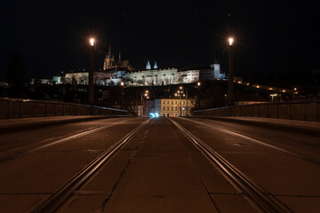 .tracks for the tram on the road and in the background Prague Castle in the center of Prague and light from the street lights
