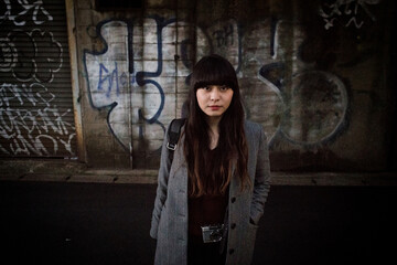 グラフィックアートの前に立つロングヘアの日本人女性