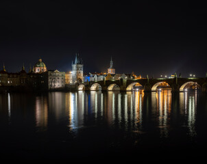 .panoramic view of Charles Bridge and illuminated street lights and the surrounding old architecture in the center of Prague in the Czech Republic at night