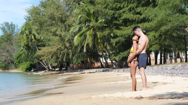 Romantic young couple standing under the sun in the calm and exotic beach.