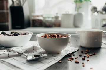 Frozen blackberries, granola, cream, towel on table. Blurred background