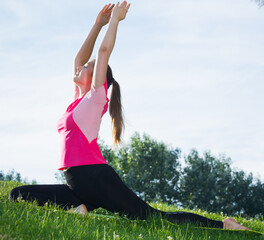 Female 20-30 years old is practicing stretching in pink T-shirt in the park.