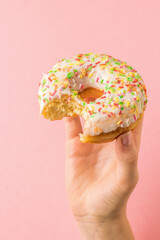 Girl's hand holding a half-eaten glazed doughnut.
