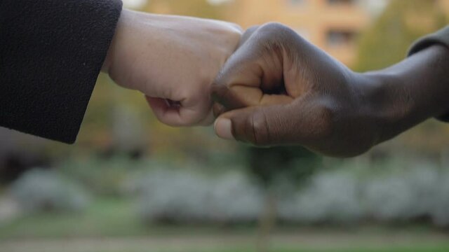 symbol of interacial friendship - fists of black and white man touch each other