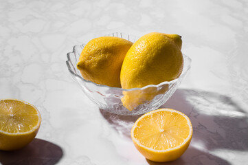 glass bowl with lemons on a white background. High in antioxidants, vitamins, dietary fibre and...
