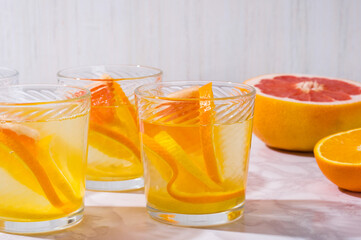 citrus lemonade and ingredients on white table. Fresh  mixed fruits drink. Healthy eating, dieting