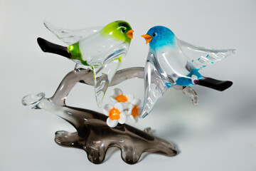 Pair of glass birds on a gray glass branch made in Murano, Italy. Handmade. White background. - obrazy, fototapety, plakaty
