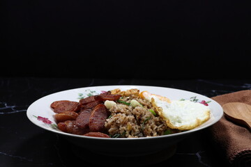 Traditional special fried rice topping with fried egg and sausage serving on the plate. 
