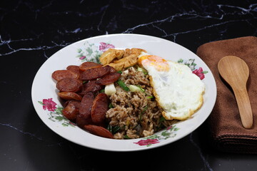 Traditional special fried rice topping with fried egg and sausage serving on the plate. 